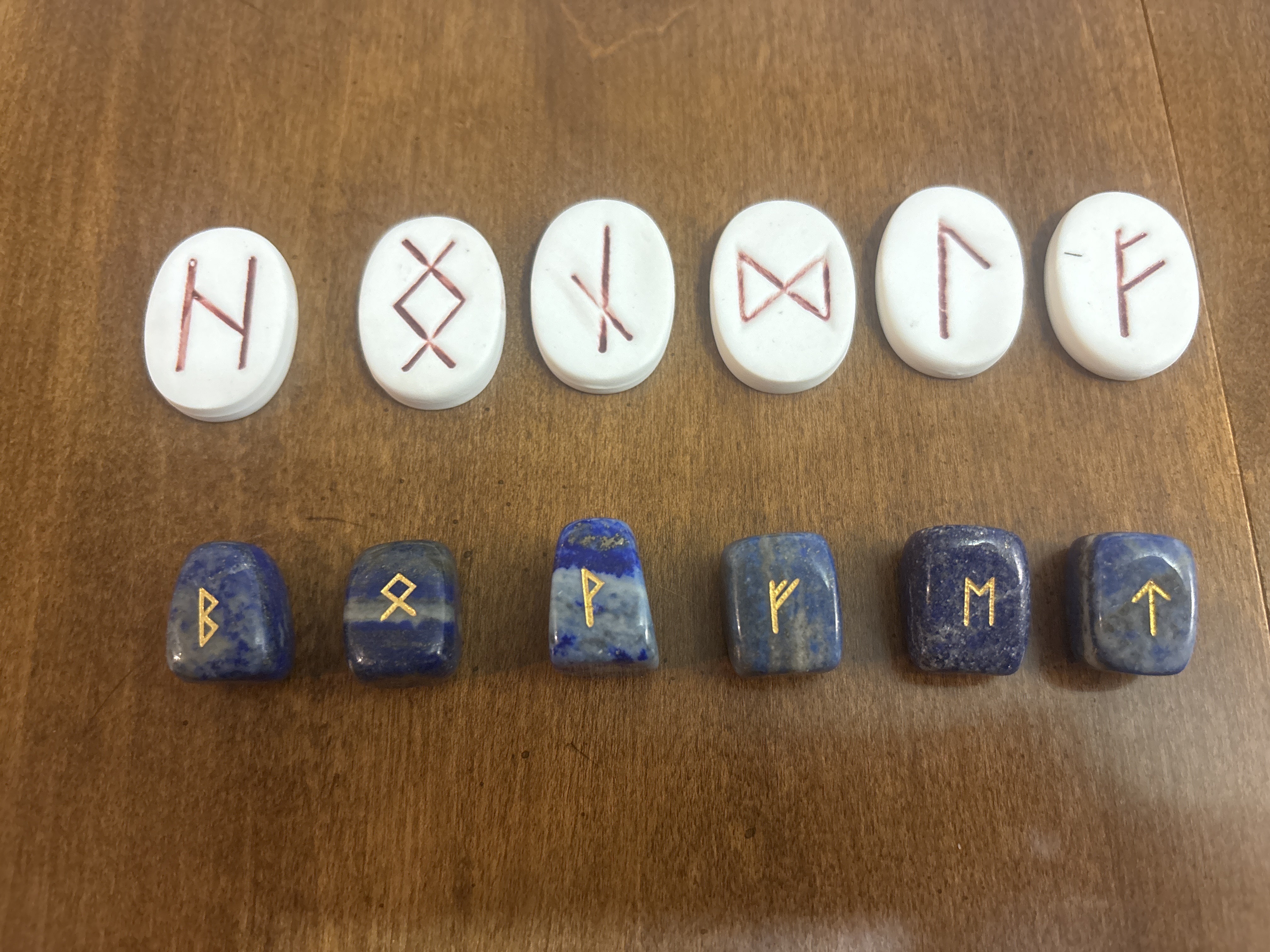White ceramic runes with red symbols arranged above blue lapis lazuli runes with gold symbols