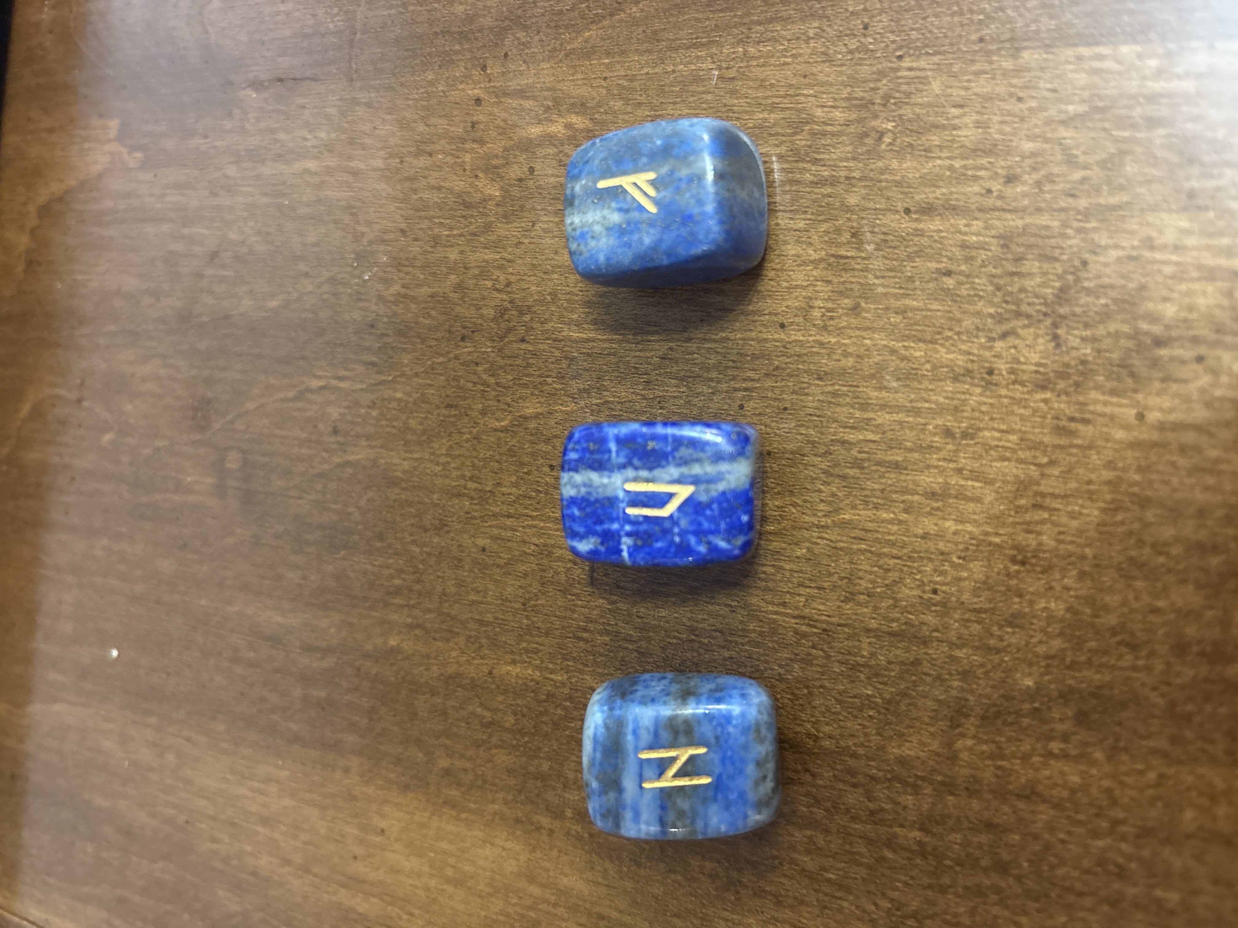 Three individual lapis lazuli runes displayed on a wooden surface