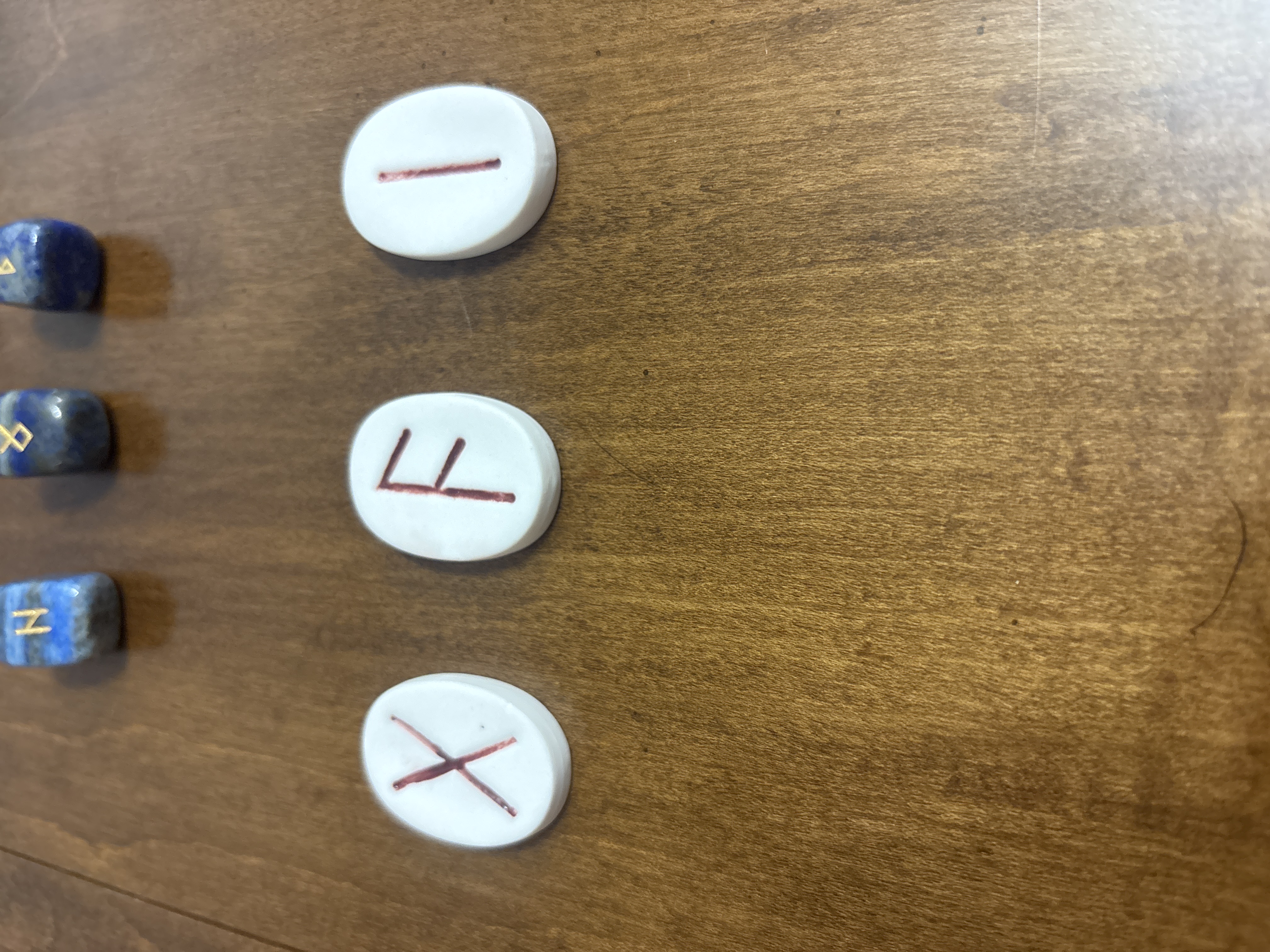 Three white ceramic runes with hand-painted red symbols