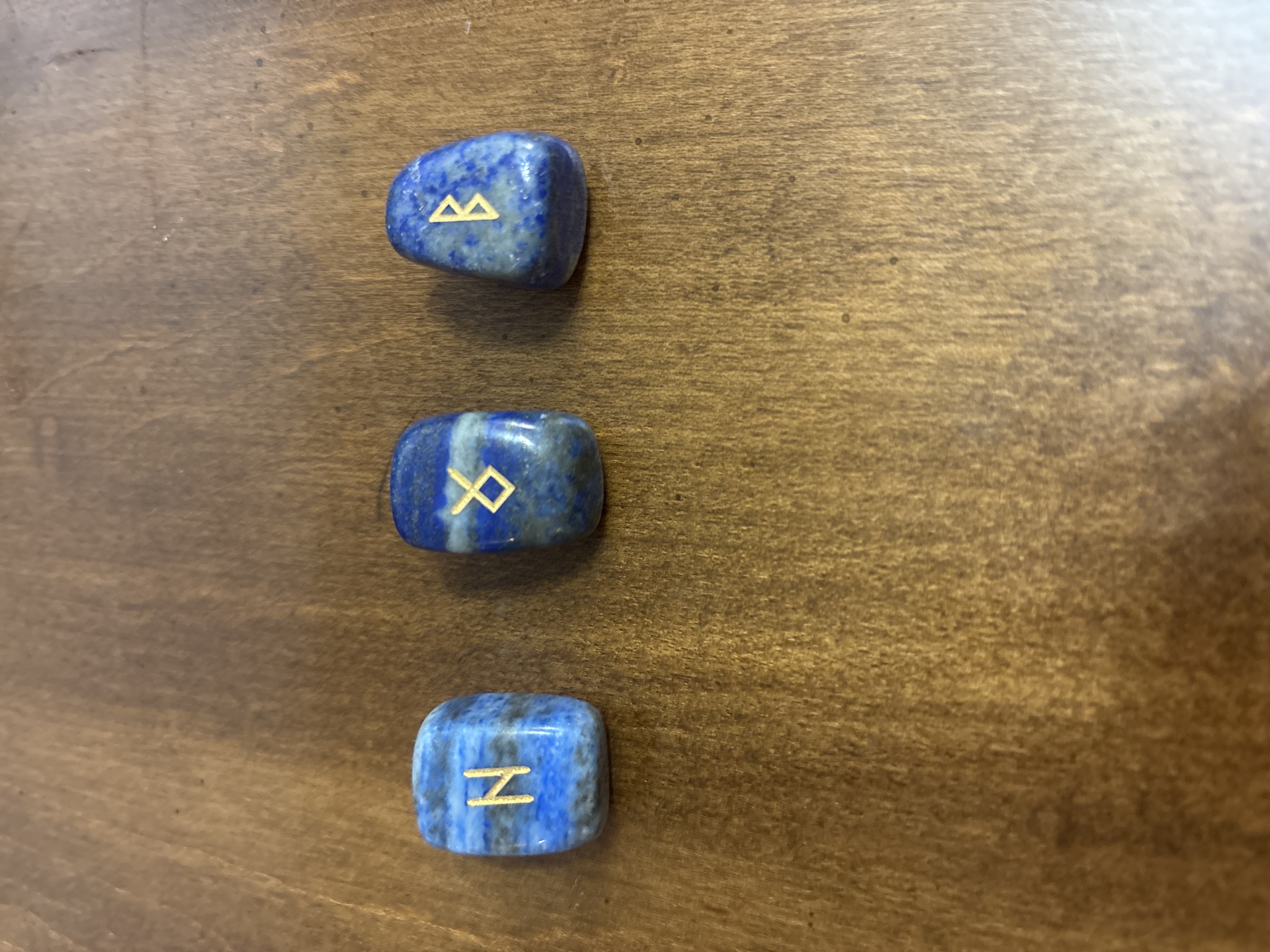 Three polished blue lapis lazuli runes engraved with gold symbols